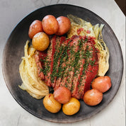 Plated dish with meat, cabbage, and potatoes on a textured surface