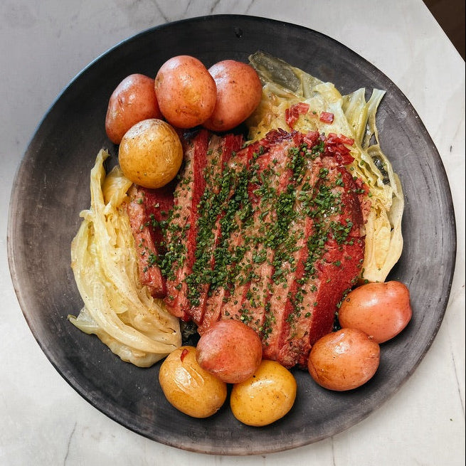 Plated dish with meat, cabbage, and potatoes on a textured surface