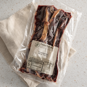 A vacuum-sealed package of Primal Pasture Korean Bone-in Spare Rib Thick Cut raw beef, resting on a beige cloth over a speckled white countertop.