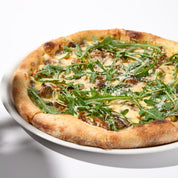 A pizza topped with ground Italian chicken sausage, cheese, and arugula, served on a white plate.