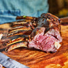 Grilled rack of lamb on a wooden cutting board with a knife